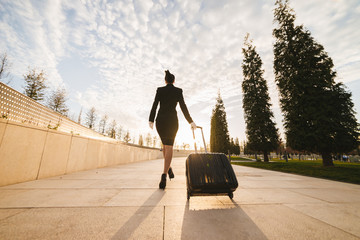 a female flight attendant in the form carries a large suitcase