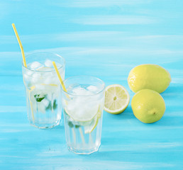 homemade lemonade with straws for drinking - lemon, mint, ice and water in glasses