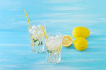 homemade lemonade with straws for drinking - lemon, mint, ice and water in glasses