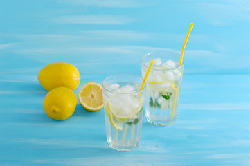 homemade lemonade with straws for drinking - lemon, mint, ice and water in glasses