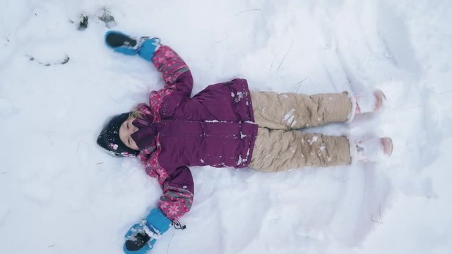 Young girl makes a snow angel. Overhead shot