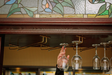 Hand with clean glass on a bar rack.