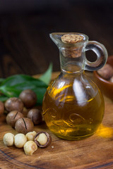 Natural macadamia oil in a glass bottle with macadamia nuts on wooden board.