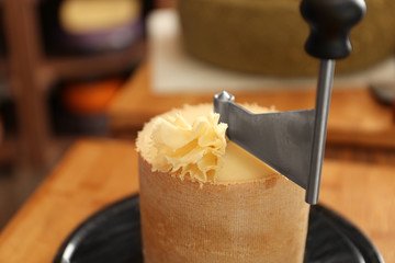 Delicious cheese scraped with girolle in shop, closeup