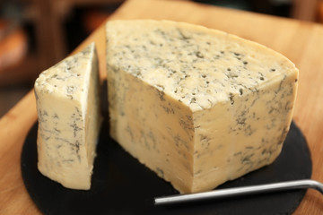 Slate plate with piece of delicious cheese on table in shop