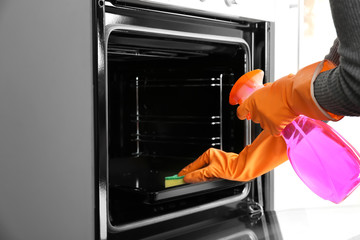 Housewife cleaning baking pan in oven