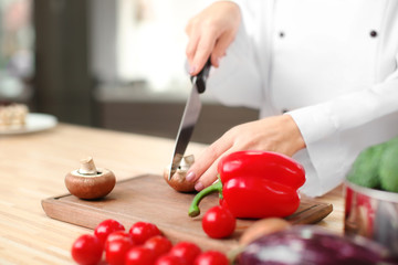 Female chef cutting vegetables in kitchen, closeup