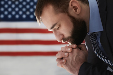 Man praying on American flag background © Africa Studio