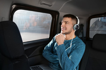 Man listening to audiobook through headphones in car