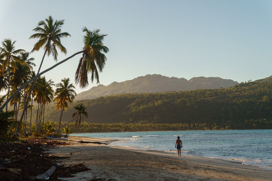 lonely man runs along a sandy beach on a tropical beach at sunrise