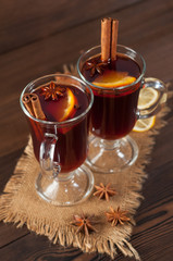 Red mulled wine on burlap on a wooden table with various spices