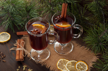 Red mulled wine on burlap on a wooden table with various spices