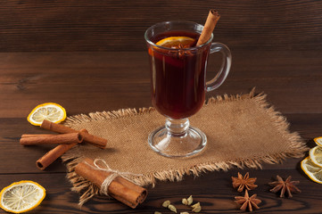 Red mulled wine on burlap on a wooden table with various spices