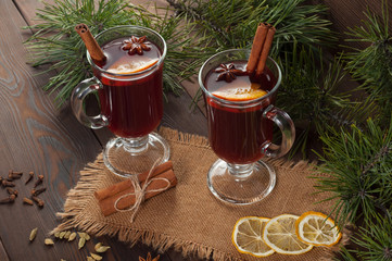 Red mulled wine on burlap on a wooden table with various spices