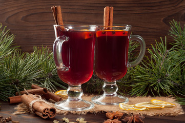 Red mulled wine on burlap on a wooden table with various spices