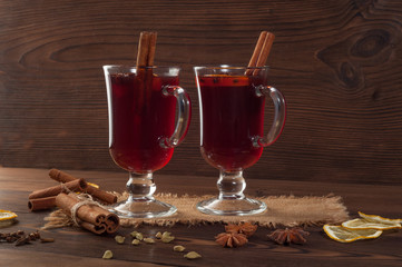 Red mulled wine on burlap on a wooden table with various spices