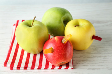 Apples with gummy worms on table. April fools food