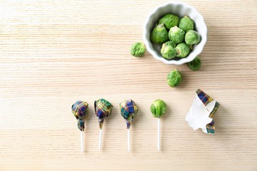 Brussel sprouts with lollipop sticks in candy wrappers on table. April fools food