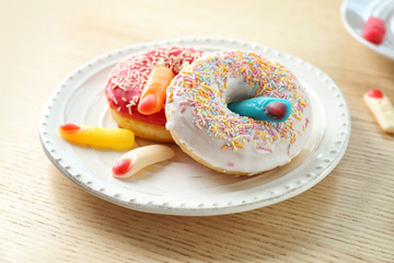 Plate with doughnuts and jelly fingers on table. April fools food