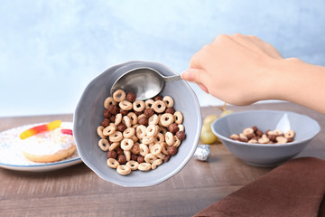 Woman holding bowl of cereal with glued spoon, closeup. April fools food