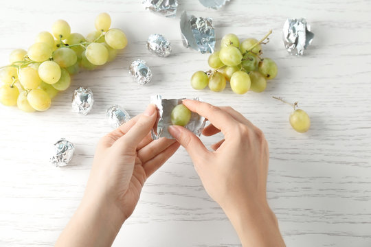 Woman Wrapping Grape In Candy Foil, Closeup. April Fools Food