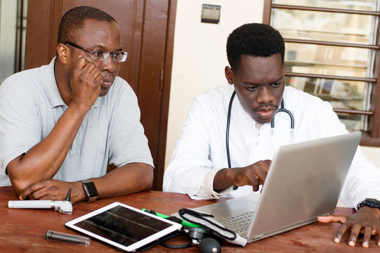 doctor and his patient sitting in front of a laptop in his office.
