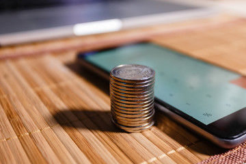 The concept of saving money and coin around with a smartphone with a calculator app for a growing business concept. Stacking Coins closeup