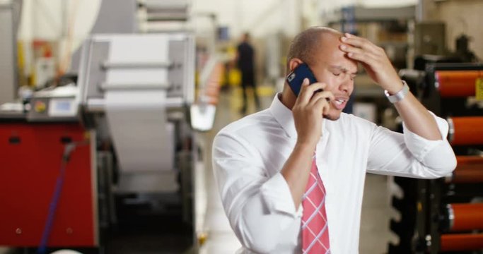 4K Frustrated & annoyed businessman in factory dealing with business problems over the phone