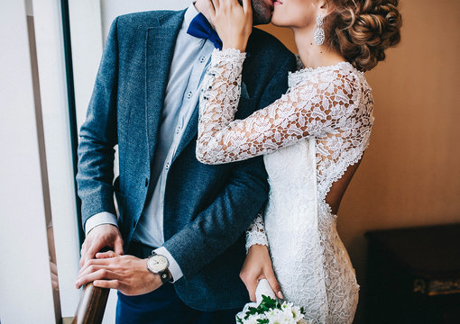 wedding couple, the bride holding the groom by the shoulder and a wedding bouquet of chamomiles