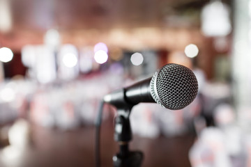 Microphone close-up. Focus on mic. Abstract blurred conference hall or wedding banquet on background. Event concept