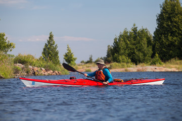 Active senior paddling a sea kayak on Georgian Bay, Ontario, Canada.