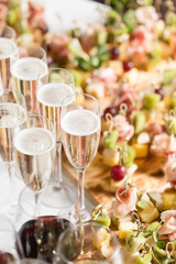 Furshet. Table top full of glasses of sparkling white wine with canapes and antipasti in the background. champagne bubbles