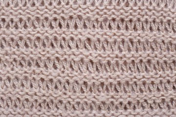 Knitted texture of beige woolen fabric with pattern. Copyspace, background