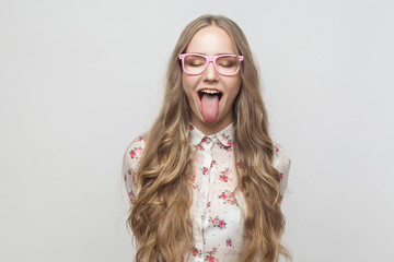 Happy and crazy concept. Teenager girl closed eyes and showing tongue at camera. © khosrork