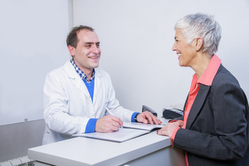 Obraz premium Senior woman paying her medical bill at the clinic with her credit card
