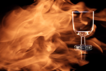 An empty glass of port or sherry in the fire flames.