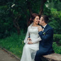 beautiful gorgeous bride and groom walking in sunny park and kis