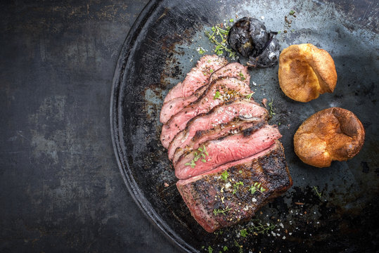 Barbecue caveman wagyu roast beef sliced with Yorkshire pudding as top view on a tray with copy space left
