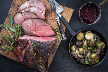Barbecue dry aged haunch of venison with mushroom and potatoes as close-up on an old cutting board © HLPhoto