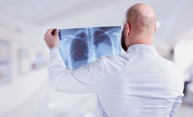 Naklejka na ściany i meble Male doctor examining x-ray