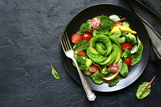 Vegetable salad with avocado, cucumber, cherry tomato, chard leaves and broccoli.Top view with copy space.