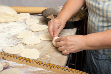 old woman baking pies in her home kitchen. Grandma cooks pies. Home cooked food. omemade mold cakes of the dough in the ederly women's hands. The process of making pie dough by hand