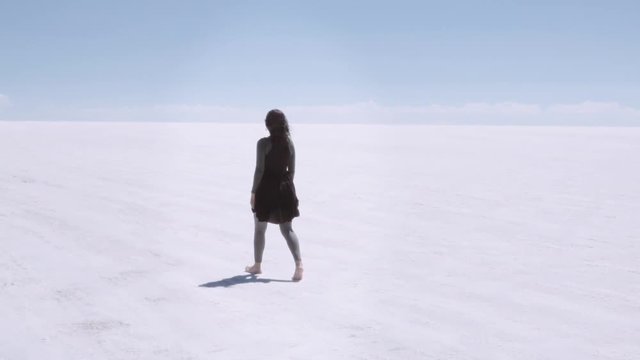 Woman walking in the infinity salt flats of Uyuni, Bolivia. Slow motion.