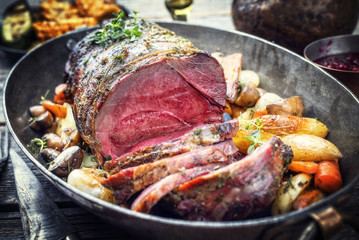Barbecue dry aged haunch of venison with mushroom and vegetable as close-up in a vintage casserole
