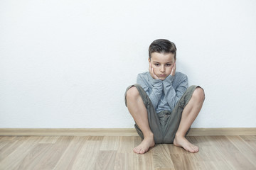 Sad boy sitting lonely in the room.Isolated on the white background