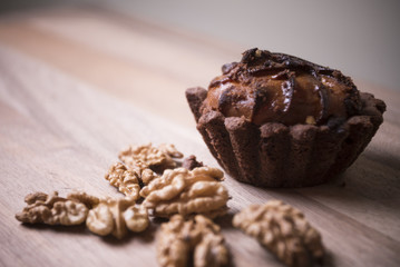 Chocolate muffin cupcake with nuts on wood background
