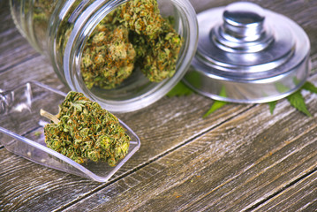 Cannabis buds (scout master strain) on glass jar over wood background