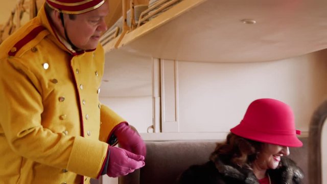 Footage in color of a lovely passenger sitting in a train cab car in stylish 1930s period attire who upon request hands her ticket to the man asking for it. (black and white version available)
