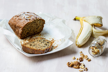 Banana bread on ceramic plate, banana fruit and walnut jar