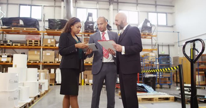 4k, Business people inspecting inventory in a large distribution warehouse.